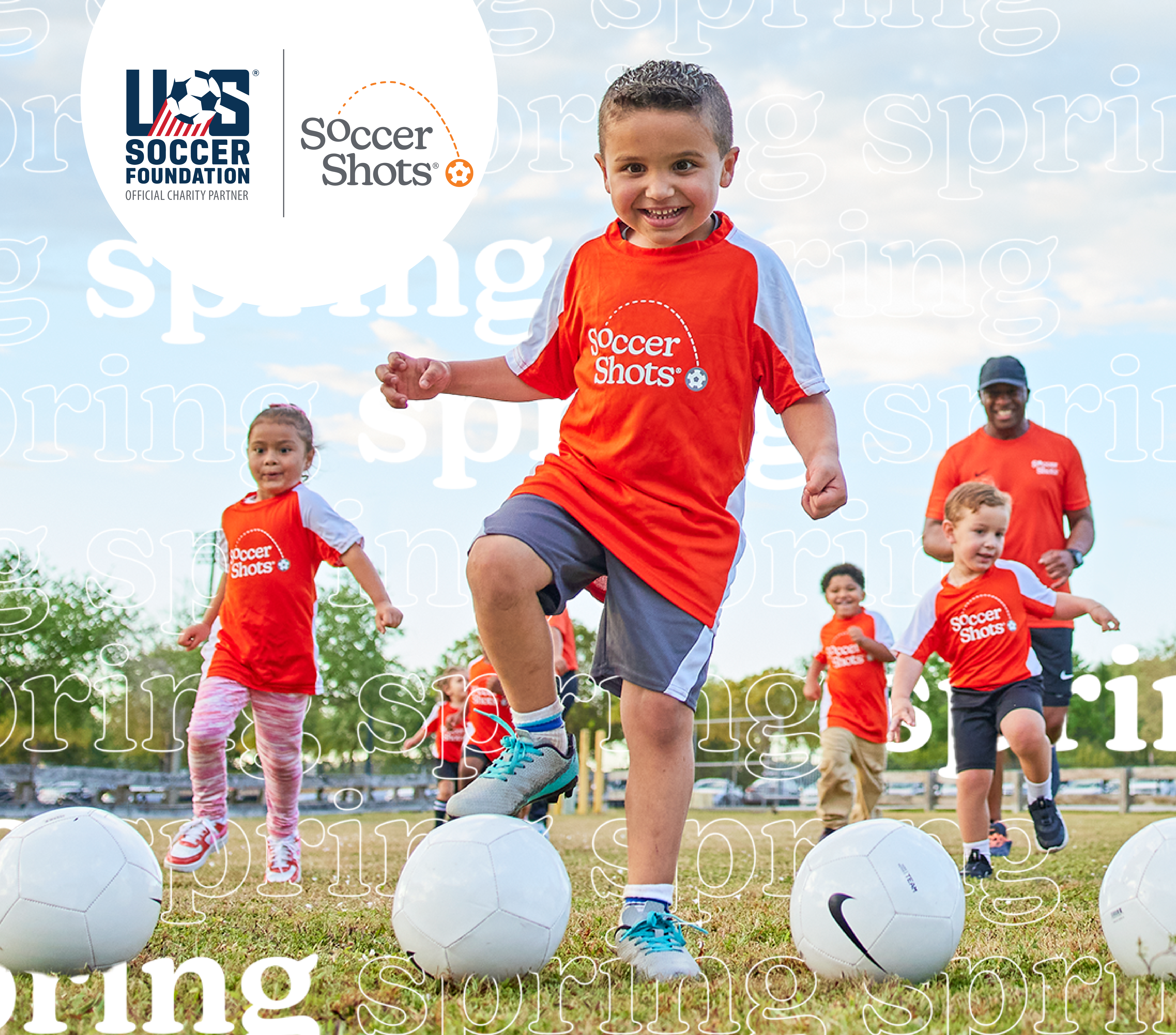 Group of children in Soccer Shots jerseys running towards a row of soccer balls.